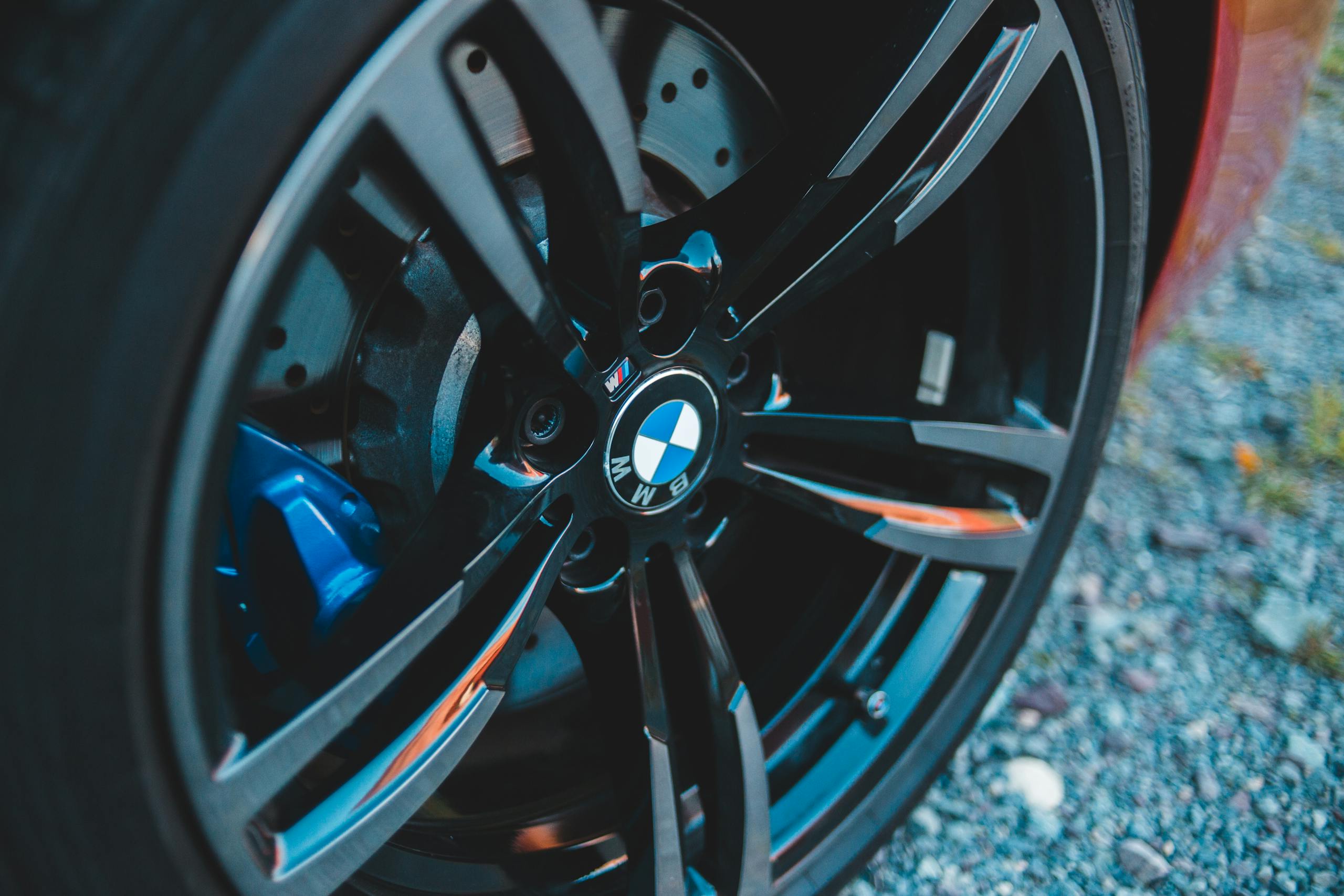 Closeup of black wheel with emblem of contemporary car placed on ground in daytime