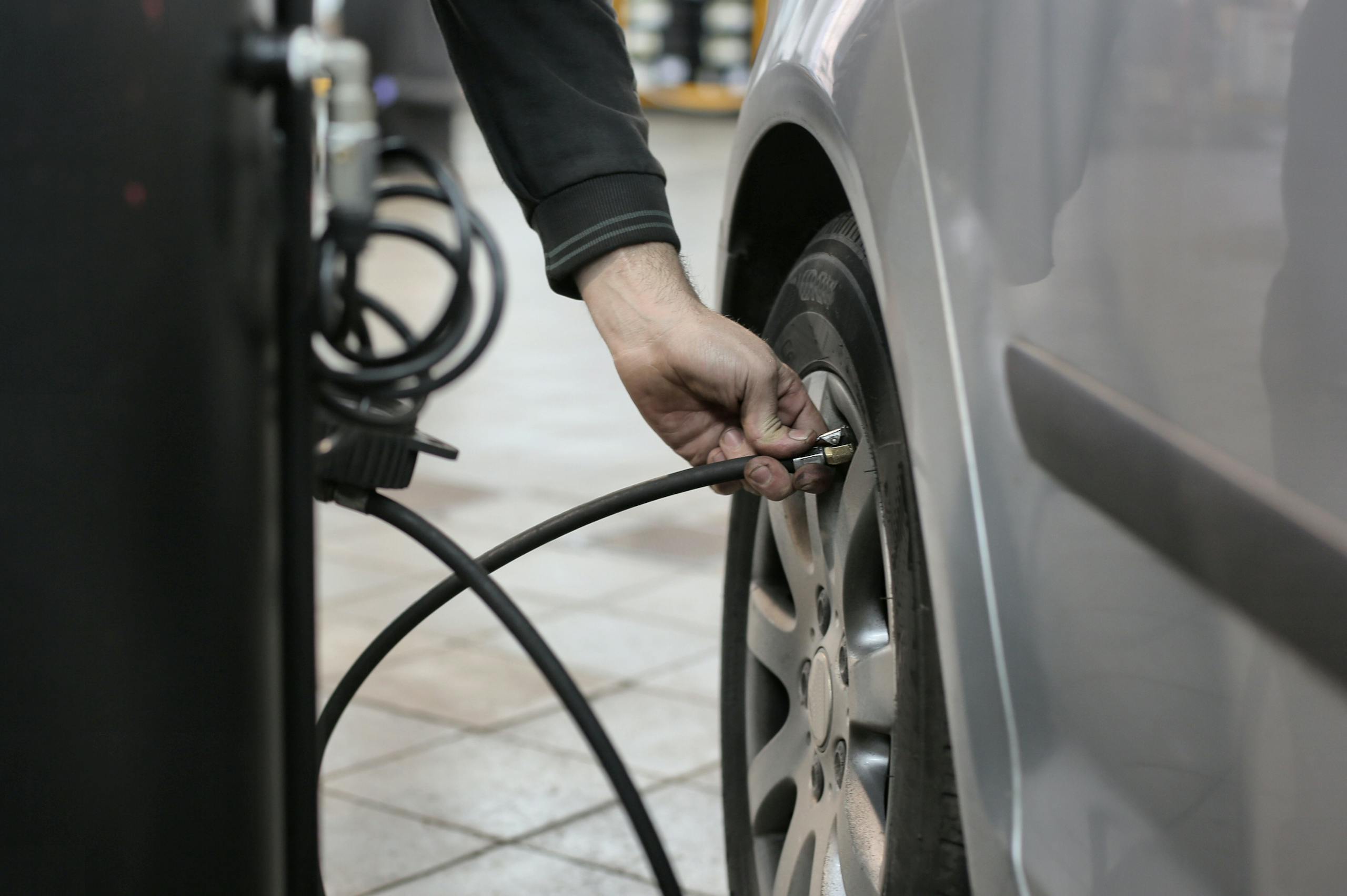 Mechanic inflating a car tire inside an auto repair shop, ensuring optimal tire pressure.
